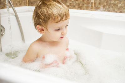 Portrait of cute boy washing hands in sink