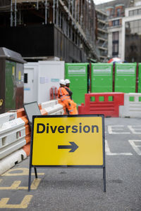 Information sign on road against buildings in city