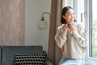 Portrait of young woman sitting on sofa at home