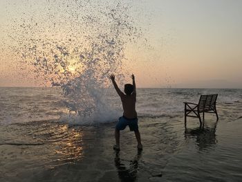 A boy at the beach enjoying splashes of  water