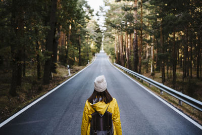 Rear view of person on road amidst trees in forest