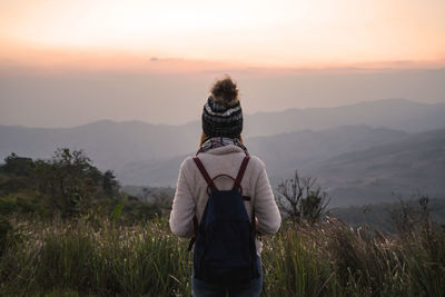 Rear view of woman looking at landscape during sunset