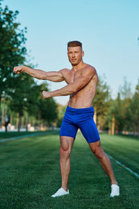 Portrait of shirtless man exercising on field