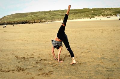 Full length of woman exercising on shore at beach