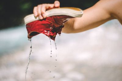 Cropped image of man holding wet red shoe