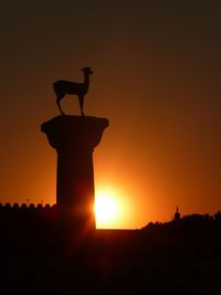 Silhouette cross on field against clear sky during sunset