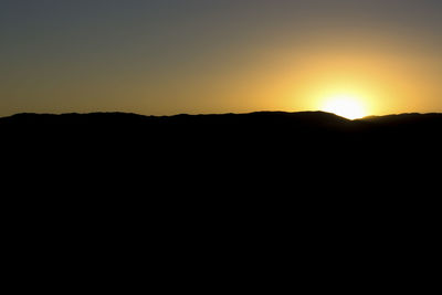 Scenic view of silhouette mountains against clear sky during sunset