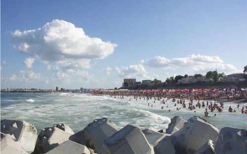 Group of people on beach in city against sky