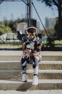 Full length of boy holding camera on staircase