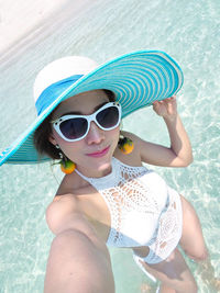 Portrait of woman wearing sunglasses standing at sea shore