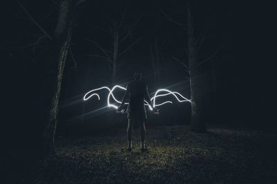 Full length of illuminated woman in dark room