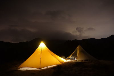 Illuminated tent against sky during sunset