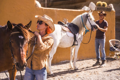 Friends preparing horses for riding