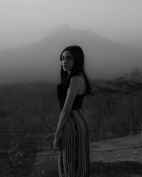 Portrait of young woman standing on land against sky
