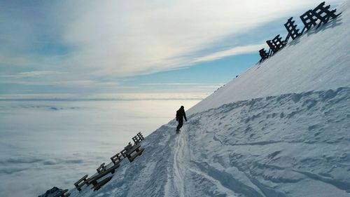 Low angle view of woman on snowcapped mountain against sky