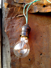 Close-up of light bulb hanging on rusty metal