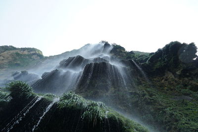 Scenic view of waterfall against sky