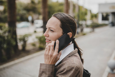 Smiling female professional talking on mobile phone while looking away