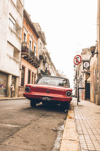 Cars on street by buildings against clear sky