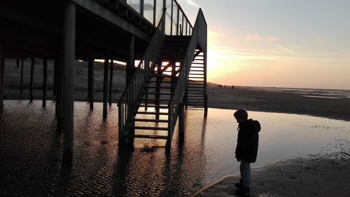 Silhouette man on beach against sky during sunset