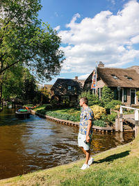 Side view of man standing on land by canal