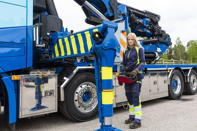 Blond female truck driver standing next to truck