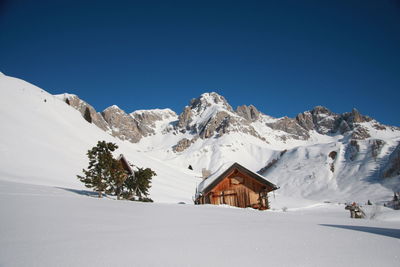 House and snowcapped mountains against clear blue sky