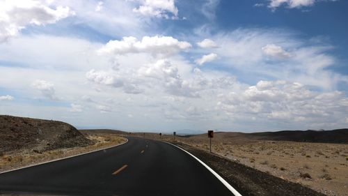 Road passing through landscape against cloudy sky