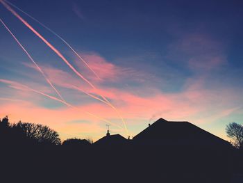 Scenic view of silhouette vapor trails against sky