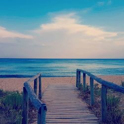 Wooden posts on beach against sky