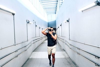 Full length of woman photographing against wall