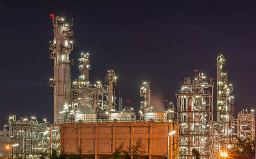 Illuminated factory against sky at night