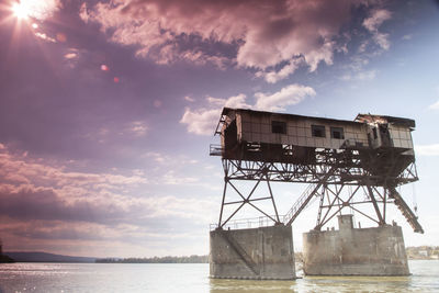 Built structure by sea against sky during sunset