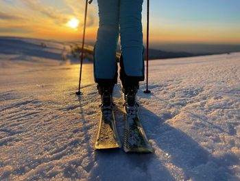 Selective focus of woman on skis at sunset