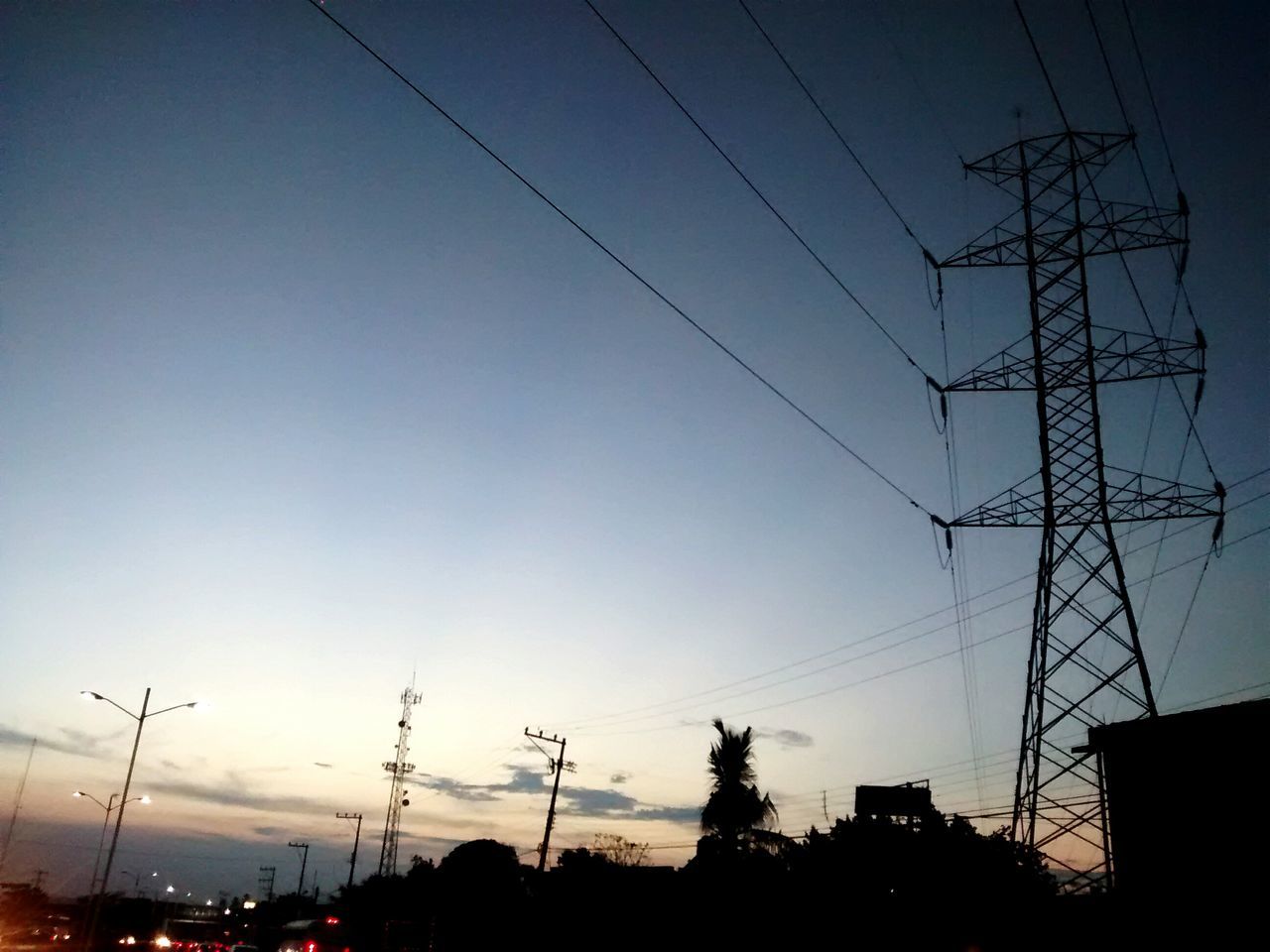 power line, electricity pylon, electricity, power supply, cable, silhouette, fuel and power generation, connection, low angle view, technology, sunset, power cable, sky, dusk, clear sky, building exterior, built structure, outdoors, no people, blue