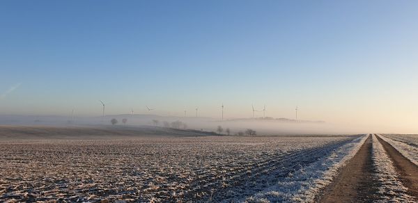 Road amidst field against sky during winter