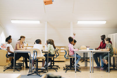 Male and female teachers teaching students in classroom at school