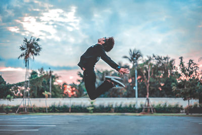 Side view of man jumping against trees