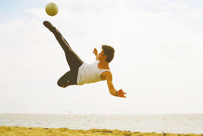 Low angle view of man playing with ball against sky