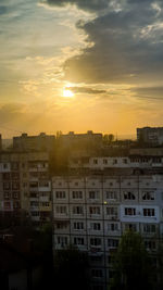 Buildings in city against sky during sunset