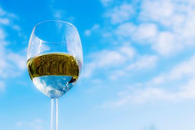 Low angle view of wine glass against blue sky