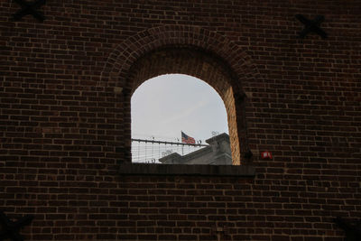 Low angle view of pigeons on window against brick wall