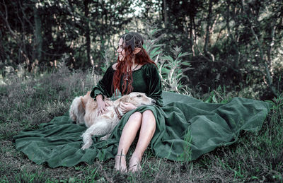 Dog sitting on street amidst trees in forest