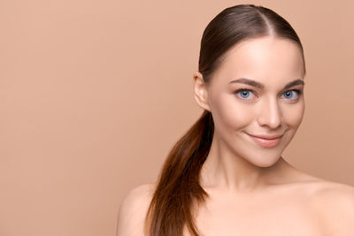 Portrait of young woman against pink background