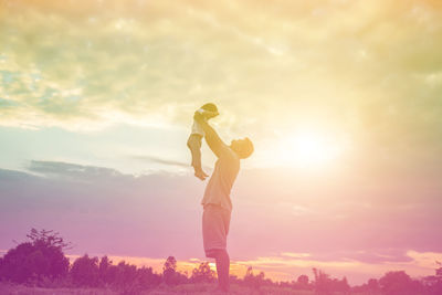 Low angle view of woman standing against sky during sunset