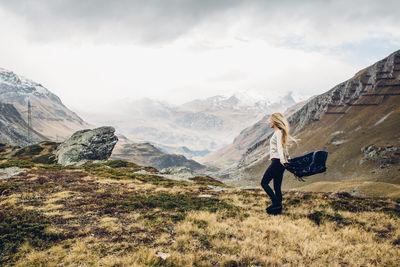 Young woman standing by mountain against sky