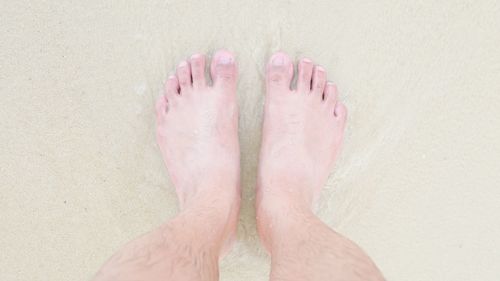 Low section of man standing on sand