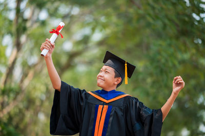 Smiling young man holding umbrella while standing outdoors