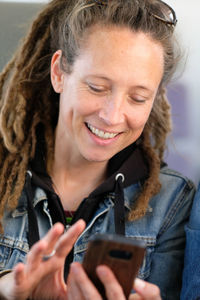 Close-up portrait of a smiling young woman using mobile phone