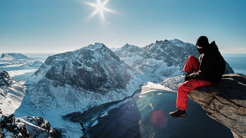 People sitting on snowcapped mountain against sky